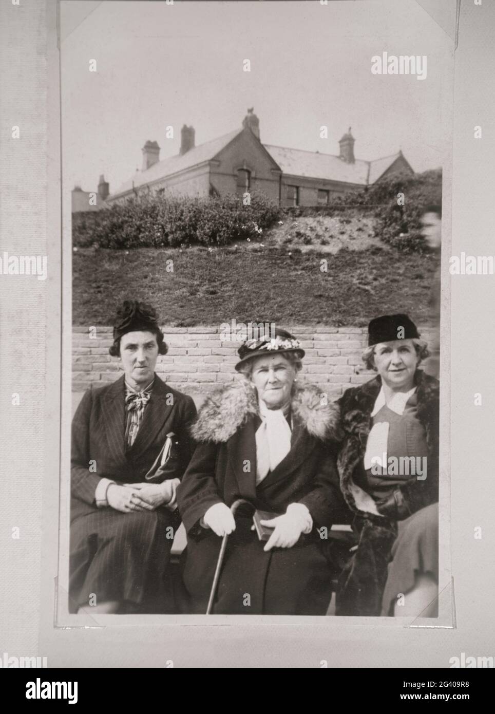 Auténtica fotografía vintage de dos mujeres jóvenes y una mujer mayor con sombreros sentados juntos. Concepto de nostalgia, el pasado, Foto de stock