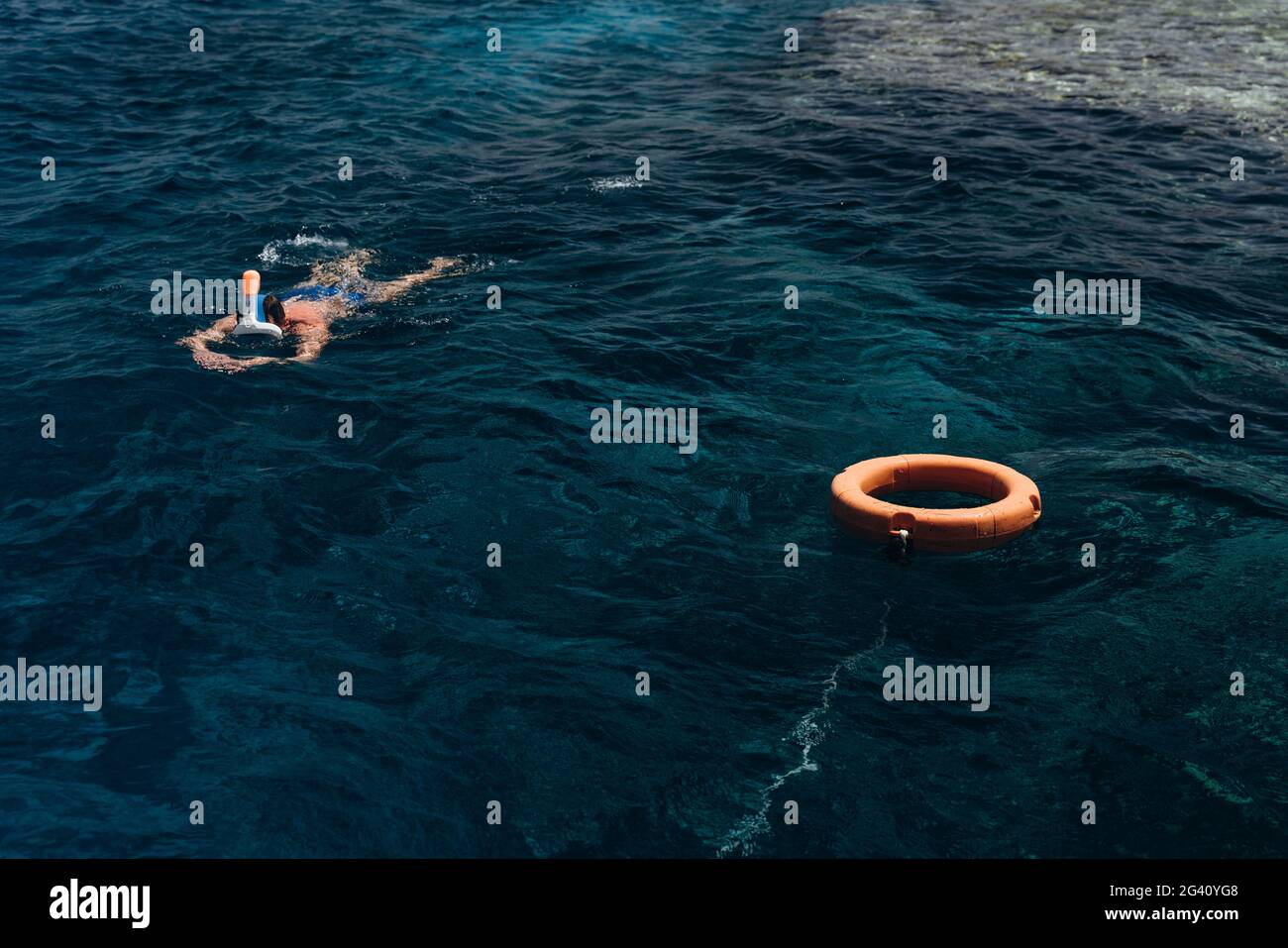 Un joven nadando con una máscara, examina peces y arrecifes de coral. Hombre descansando junto al mar. Foto de stock