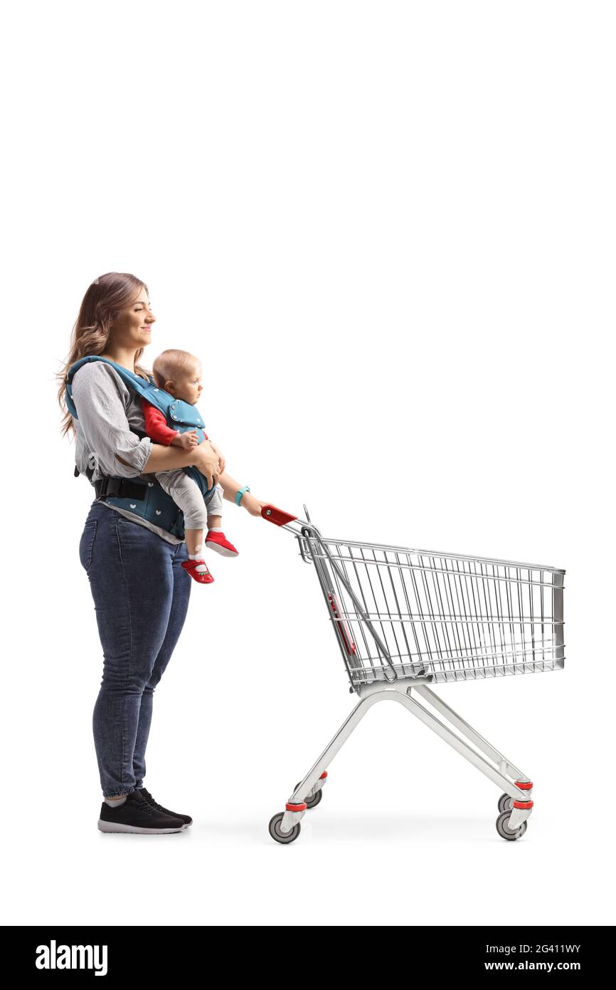 Disparo completo de una madre con un bebé en un portador empujando un carro de la compra aislado sobre fondo blanco Foto de stock