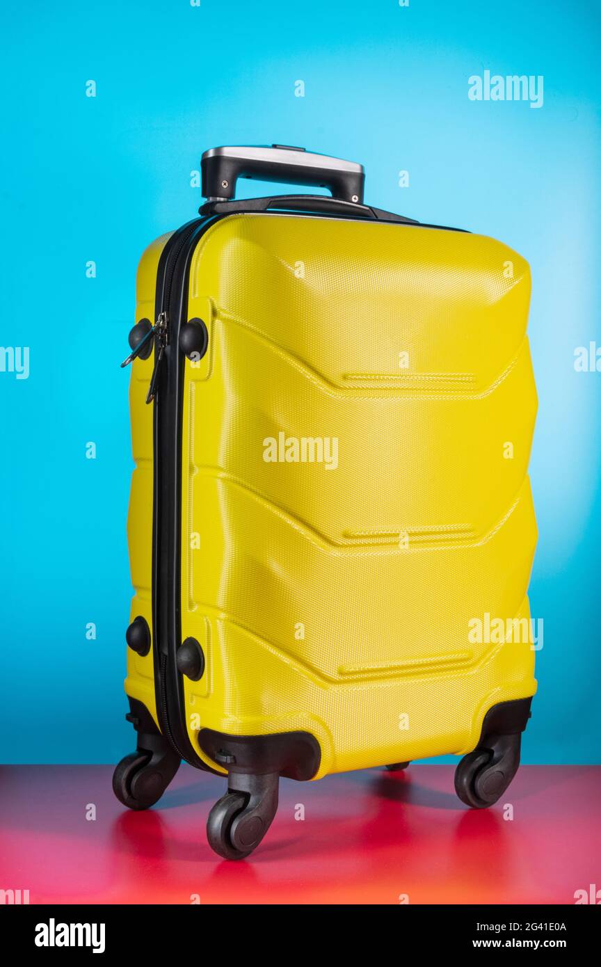Maleta amarilla en las ruedas. Maleta de equipaje en las ruedas. Maleta  amarilla sobre fondo azul. Vista frontal Fotografía de stock - Alamy