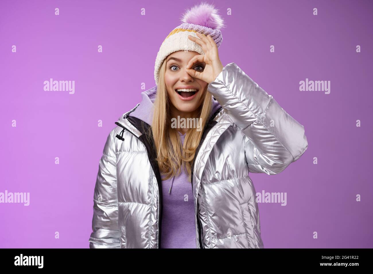 Impresionada curiosa buena mirada rubia elegante mujer viajera charged nevadas vistas mantener bien signo ojo sonriendo asombro Foto de stock