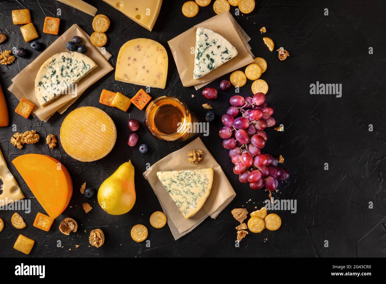 Queso y vino. Un montón de quesos con uvas y una copa de vino Foto de stock