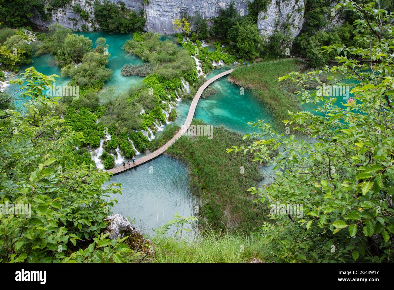 Vista de la gente en el camino de madera sobre la piscina con cascadas, el Parque Nacional de los Lagos de Plitvice, Lika-Senj, Croacia, Europa Foto de stock
