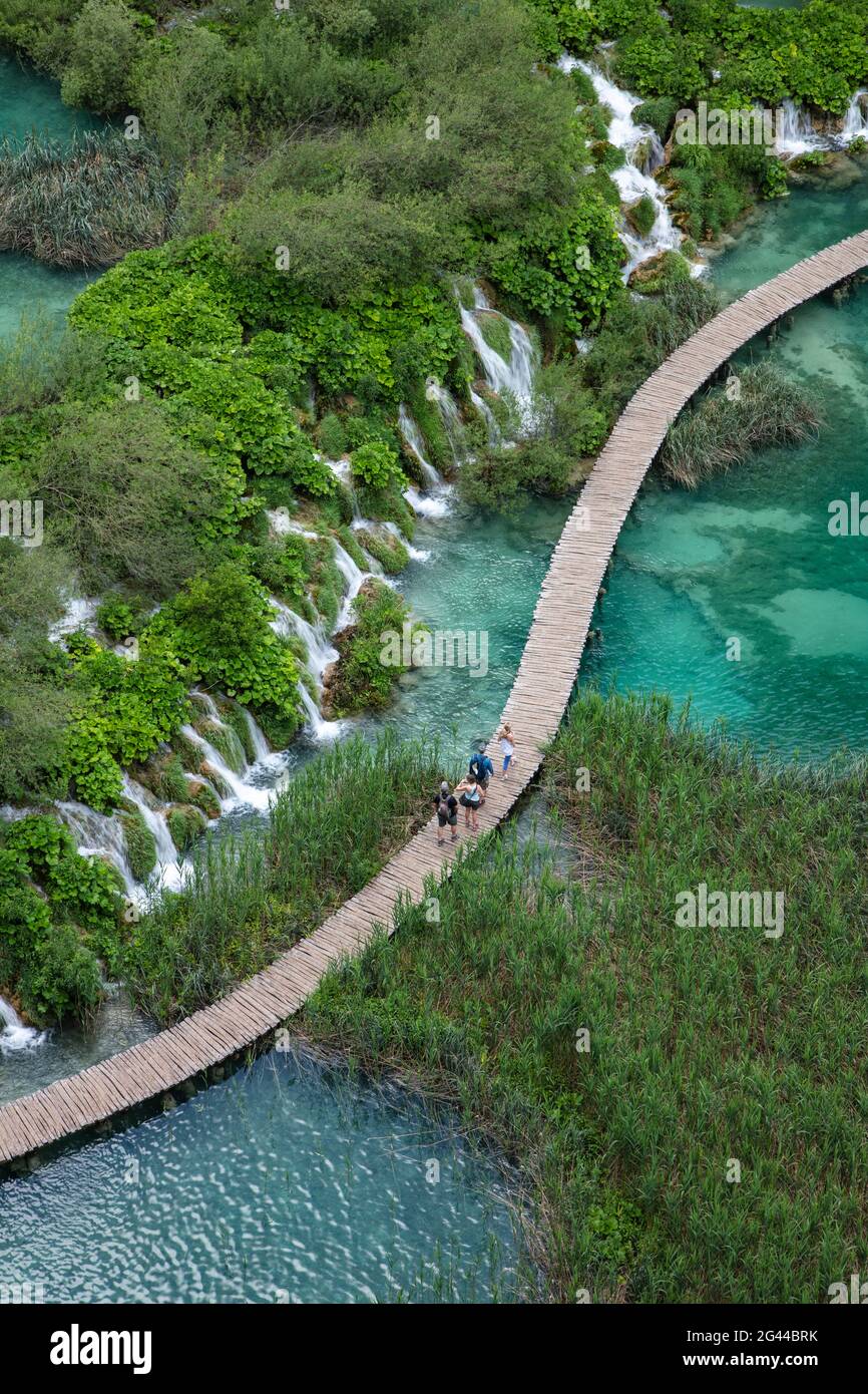Vista de la gente en el camino de madera sobre la piscina con cascadas, el Parque Nacional de los Lagos de Plitvice, Lika-Senj, Croacia, Europa Foto de stock