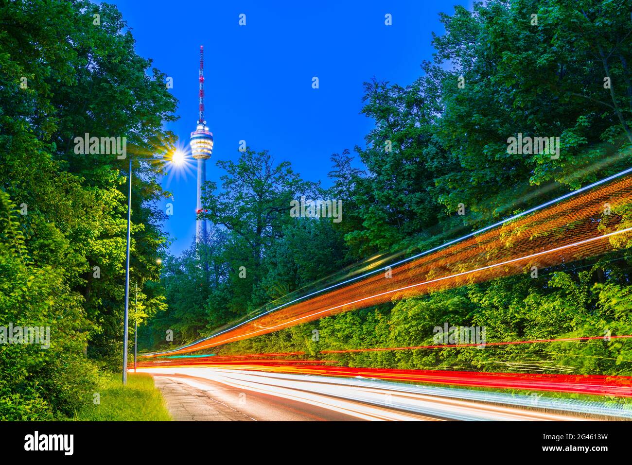 Alemania, ciudad de Stuttgart, el horizonte del edificio de la torre de televisión detrás de calles iluminadas con tráfico por la noche Foto de stock