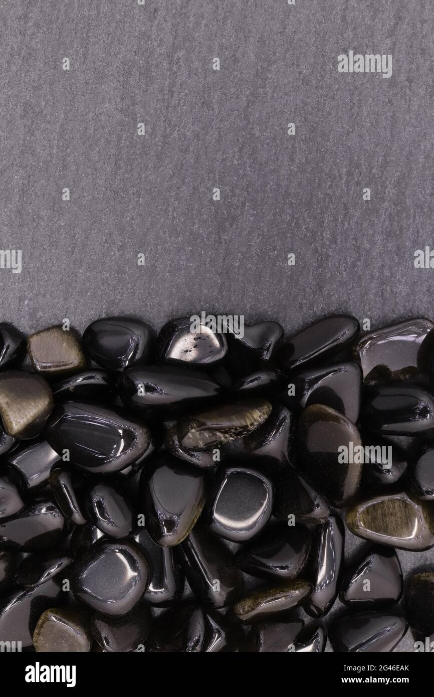 Pila de joyas de obsidiana de oro sobre fondo medio de piedra negra.  Textura de guijarros minerales en pilas. Lugar para el texto Fotografía de  stock - Alamy