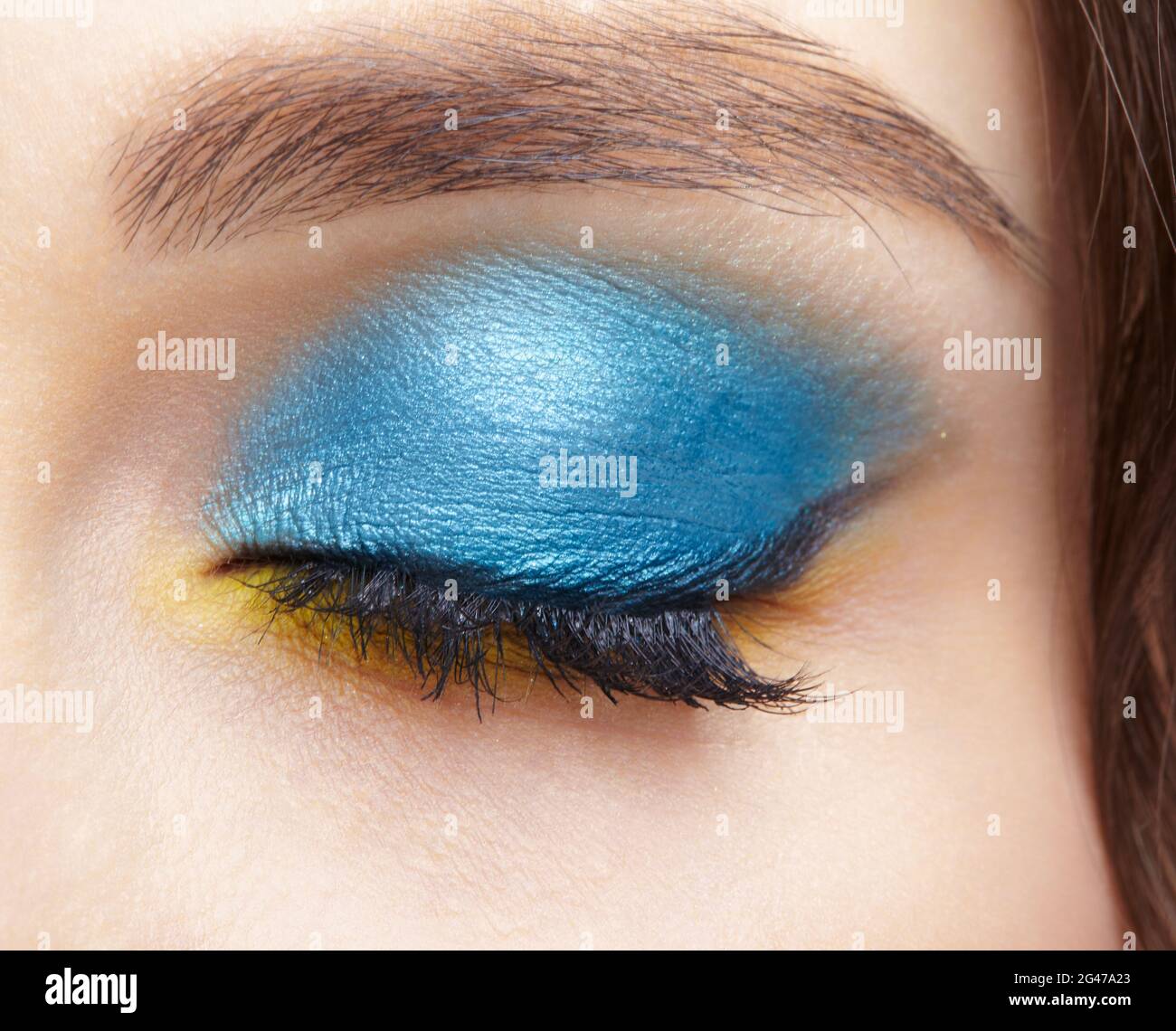 Ojo femenino humano cerrado con sombras de ojos azul ahumado y  revestimiento amarillo Fotografía de stock - Alamy