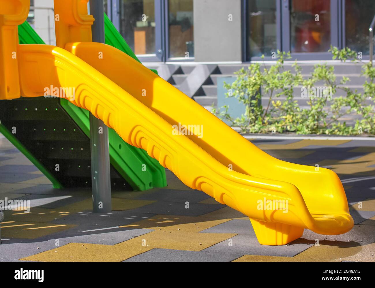 Un parque de juegos colorido con un tobogán de plástico amarillo en una  estera de goma segura. Un lugar para el entretenimiento activo de niños en  edad preescolar y escolar en A