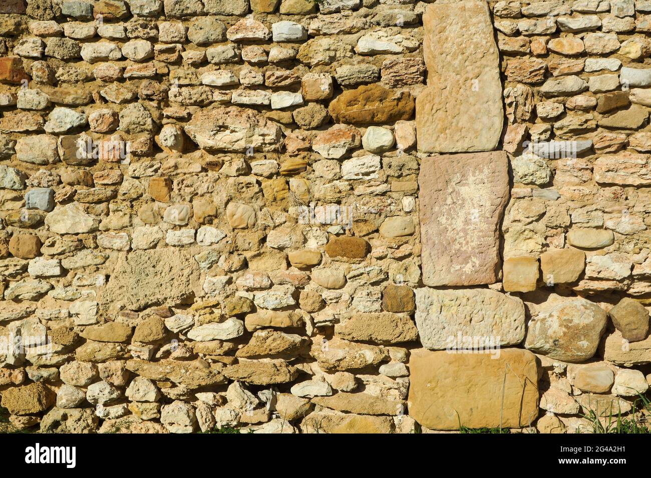 Grandes bloques verticales de piedra y pequeñas piedras horizontales en la construcción de paredes de piedra romana Foto de stock