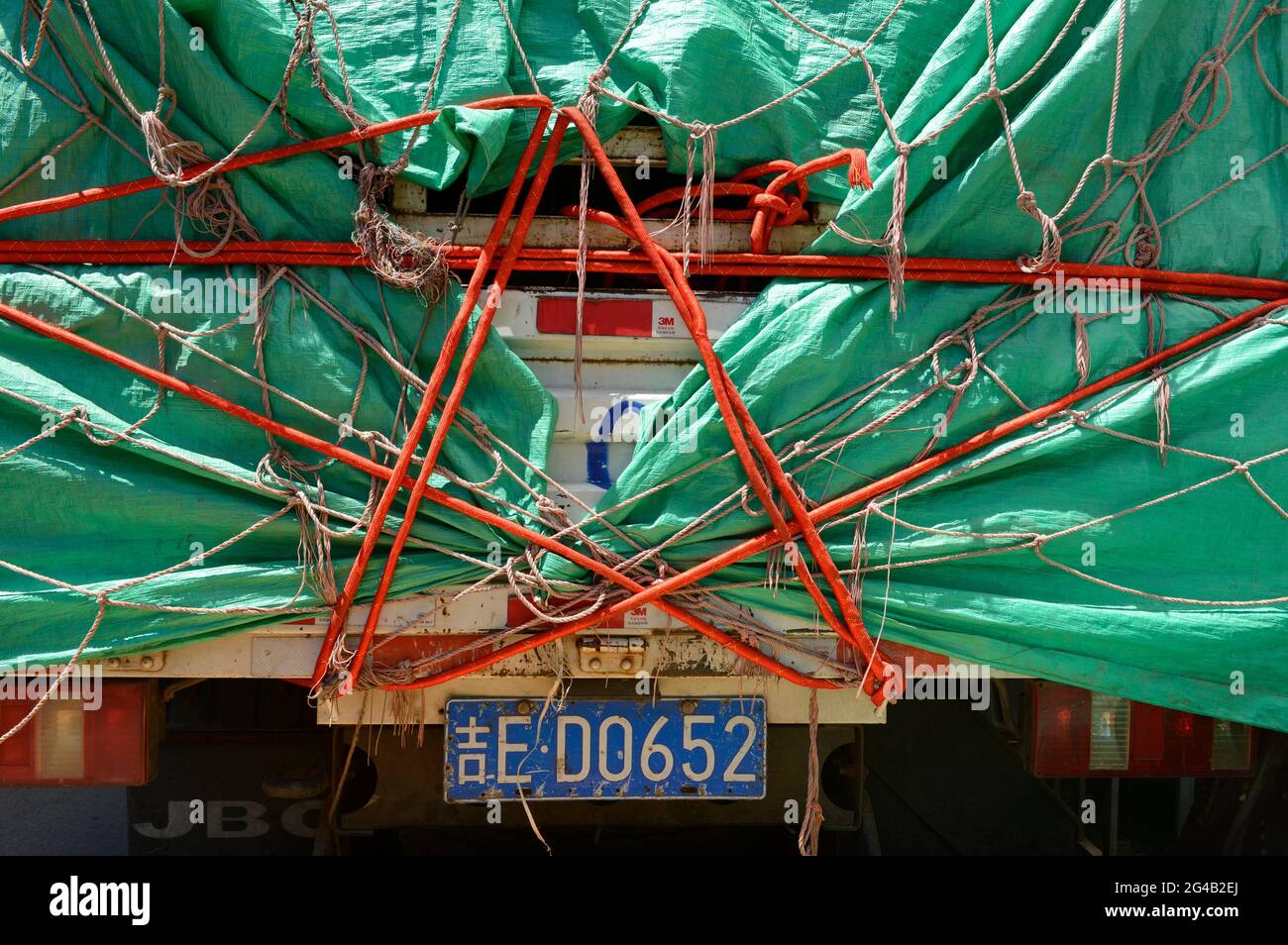 Un lienzo de plástico verde estrechamente atado cubre un camión bien cargado en Shenyang, China Foto de stock