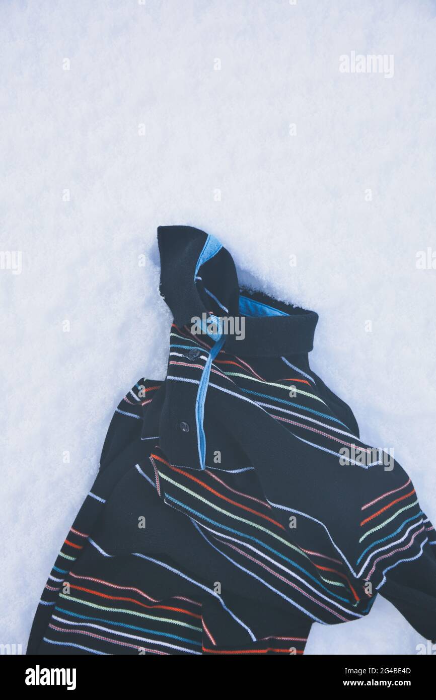 Sudadera de rayas top ropa vestir tumbado en la nieve. Concepto de abandonado, descartado, Foto de stock