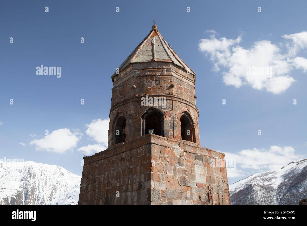 La iglesia de la Trinidad de Gergeti está bajo cielo nublado en un día soleado, Monte Kazbek, Georgia Foto de stock