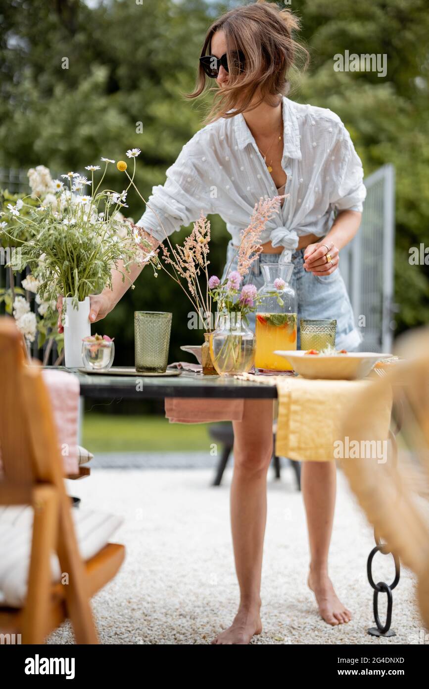 Mujer joven decorando mesa de comedor en el patio trasero de su casa.  Belleza y estética en la vida cotidiana Fotografía de stock - Alamy