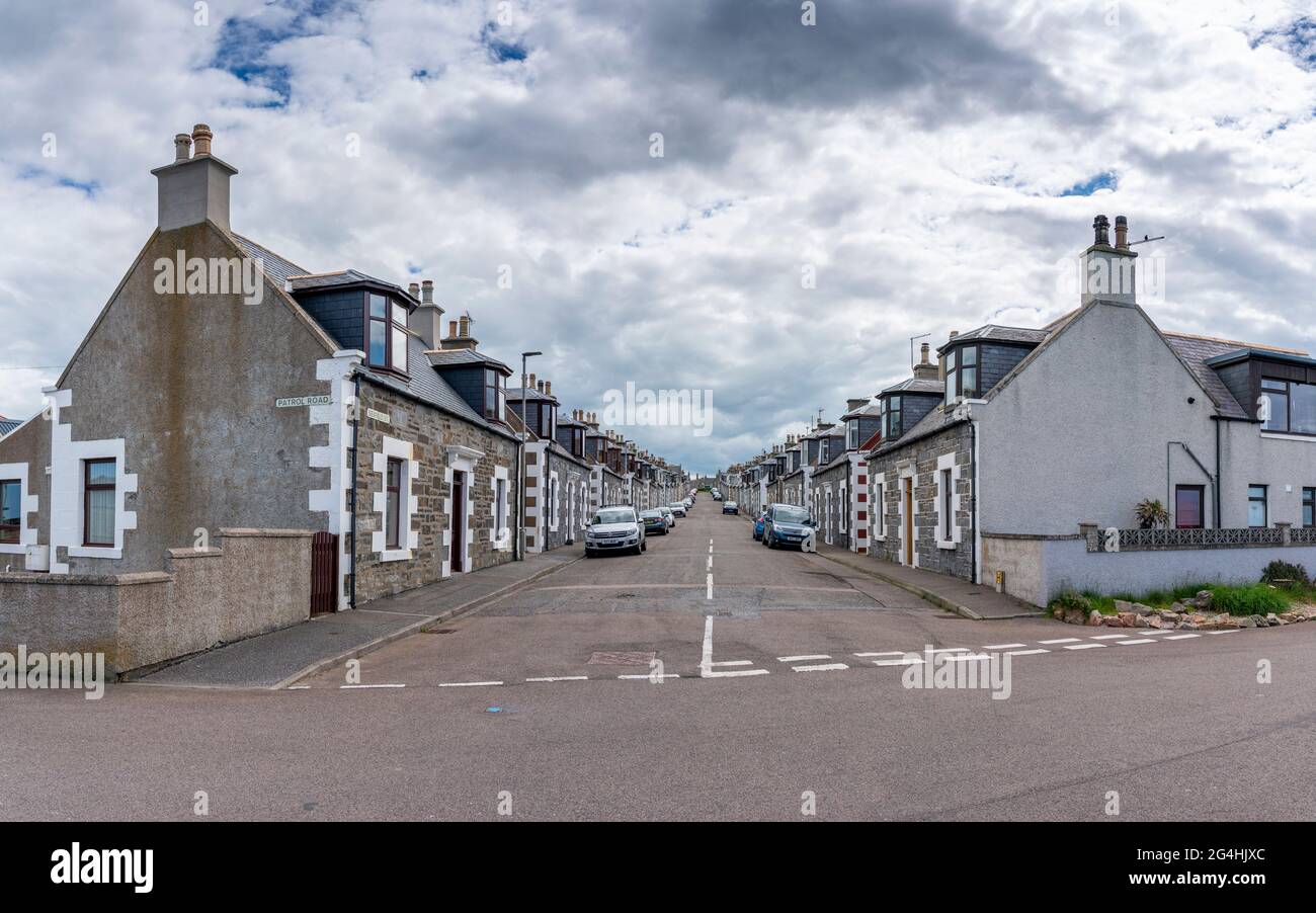 Vista a lo largo de la calle bordeada de antiguas casas de pescadores en Portknockie, Moray, Escocia, Reino Unido Foto de stock