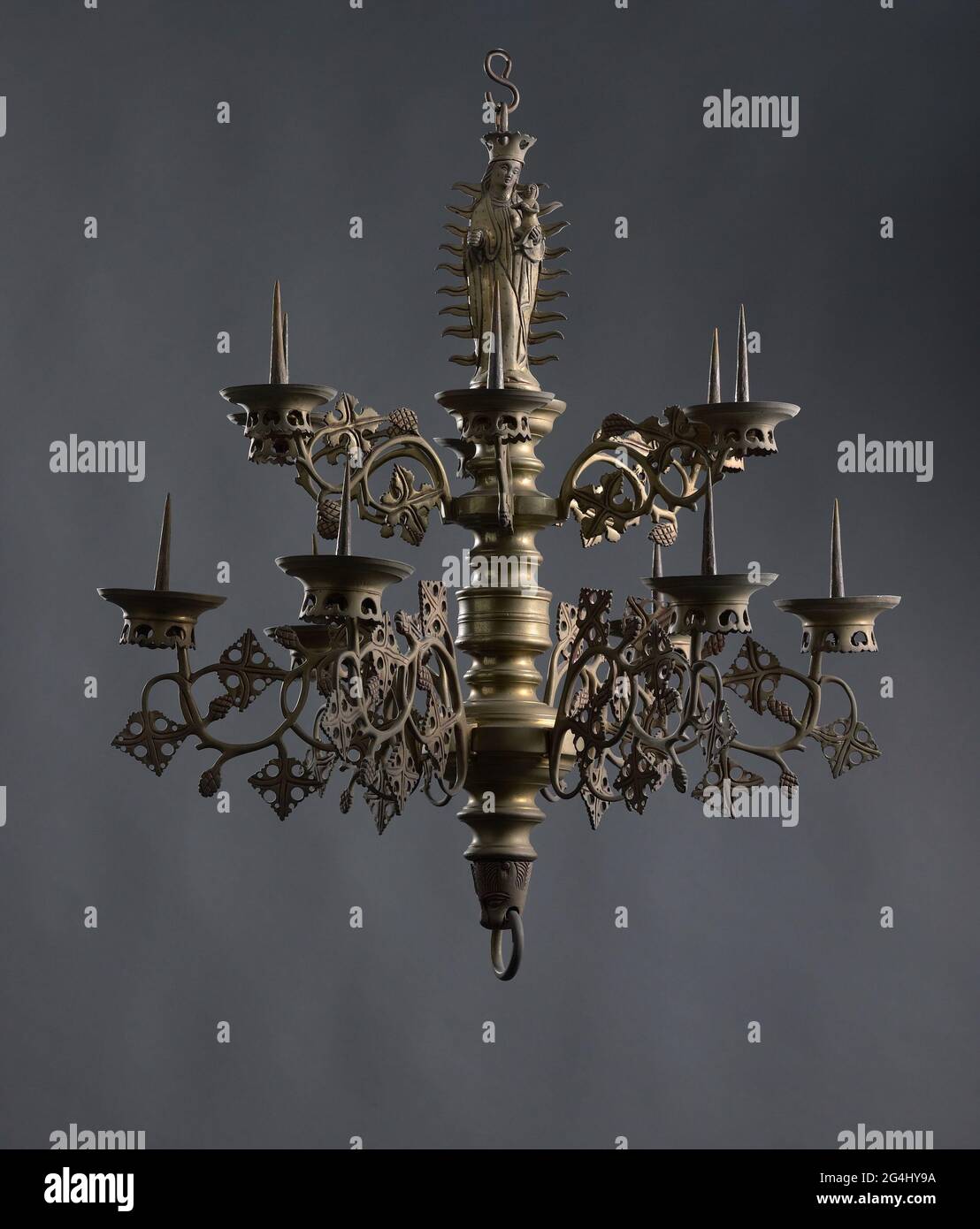 Brazo de vela perteneciente a una corona de vela de dos alturas con figura  de maría en la parte superior. El brazo se dobla dos veces y está decorado  con dos