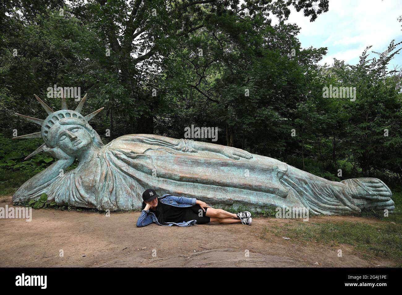 Nueva York, Estados Unidos. 21st de junio de 2021. Iveth Manjarrez adopta la misma postura que “Reclining Liberty” para unas fotos delante de la réplica de la Estatua de la Libertad de 25 pies de largo esculpida por el artista Zaq Landsberg, en Morningside Park, en Nueva York, NY, 21 de junio, 2021. (Foto de Anthony Behar/Sipa USA) Crédito: SIPA USA/Alamy Live News Foto de stock