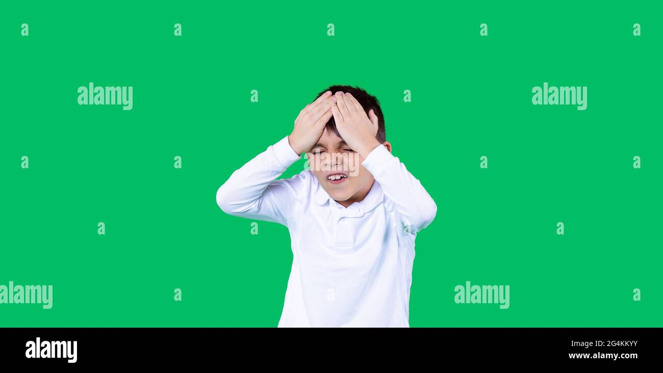 Banner, formato largo. Fondo verde. Un niño sostiene la cabeza. Está infeliz y molesto. Foto de stock
