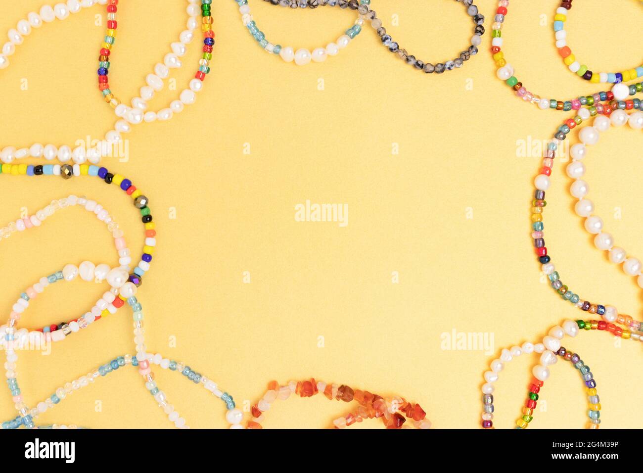 Collares y pulseras hechos de cuentas y perlas sobre un fondo dorado. Marco de borde con espacio de copia. Foto de stock