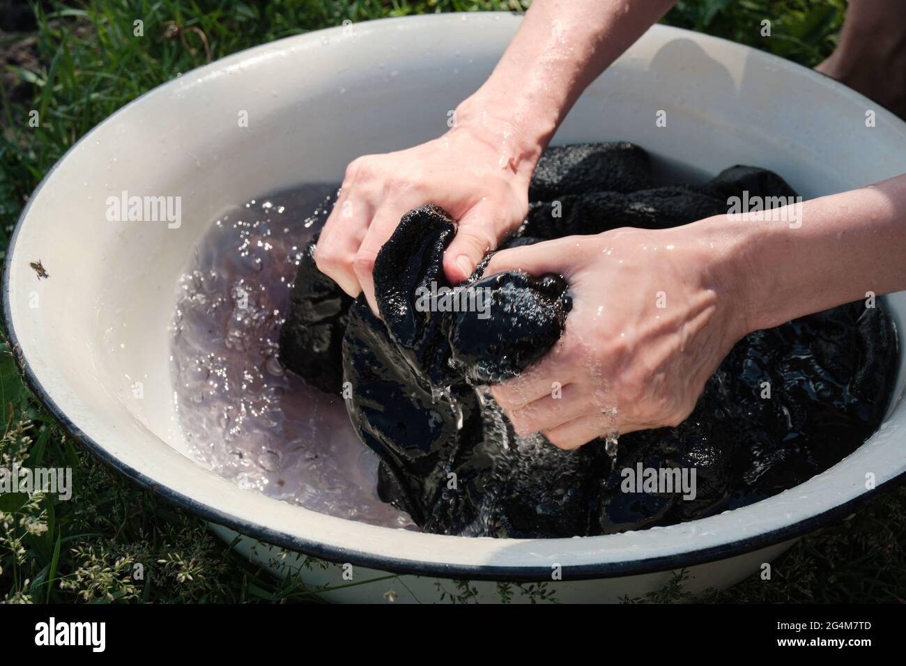 La joven lava la ropa a mano en el lavabo. Lavar a mano ropa en la naturaleza. Lavar ropa en el lago Fotografía de stock Alamy