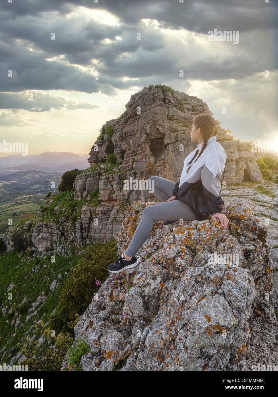 Mujer con chubasquero en el borde de un acantilado con vistas a un valle en un día lluvioso y húmedo. Imagen conceptual de tonos exteriores.Torcal de Antequera,España. Foto de stock