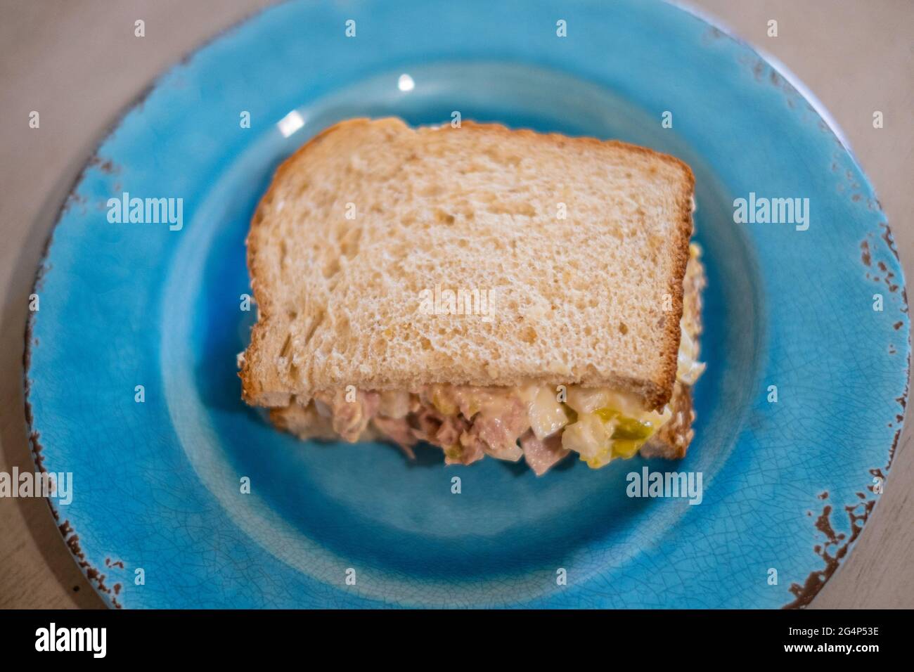 La mitad de un sándwich de atún con pan de oatnut en un plato azul. Primer plano. Foto de stock
