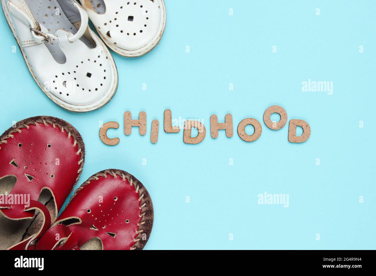 Sandalias de cuero para niños sobre fondo azul con palabra infancia  Fotografía de stock - Alamy