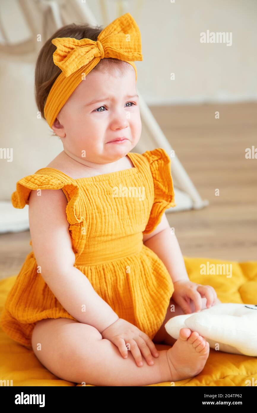 Una niña de un año de edad con ropa amarilla está disgustada y llorando,  foto de estudio para un año de niño Fotografía de stock - Alamy