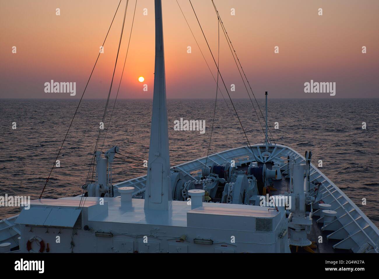Puesta de sol sobre los arcos de un barco navegando en el Océano Índico Foto de stock