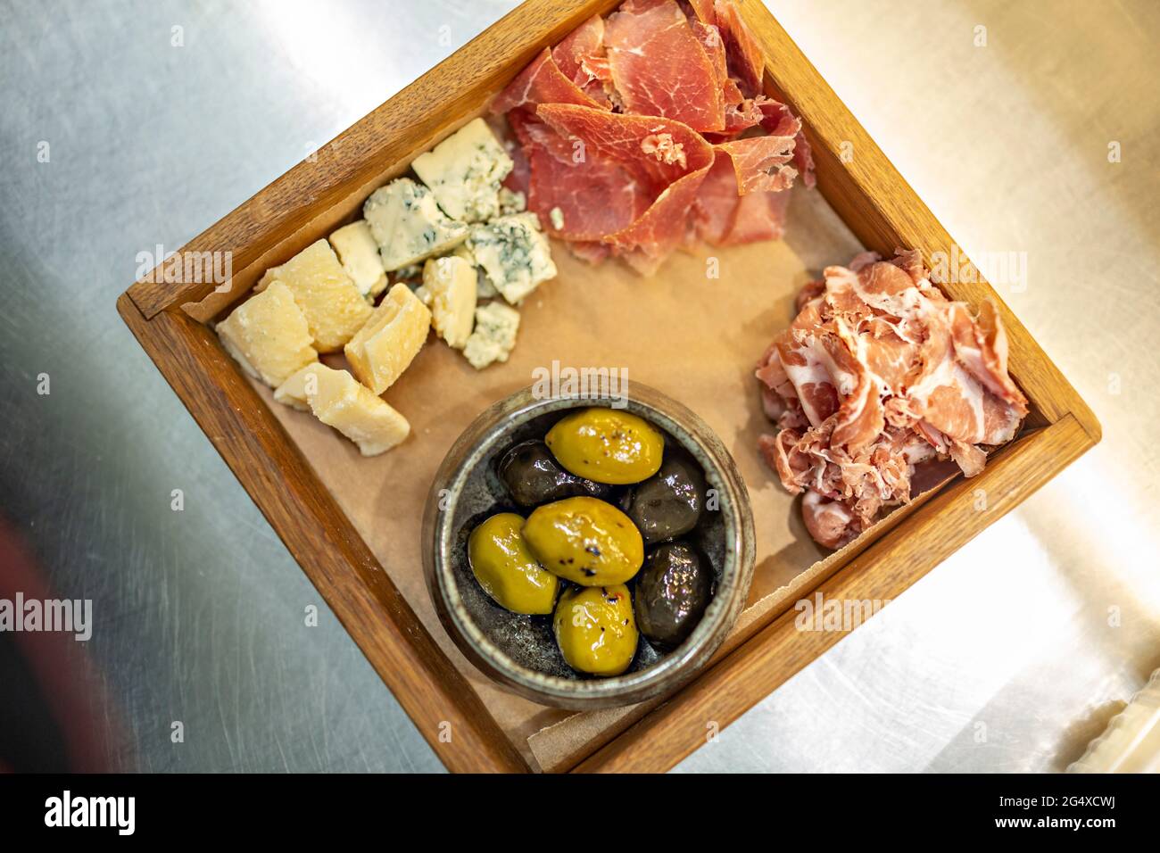 Oliva verde y negro servido con carne roja y queso en bandeja de madera Foto de stock