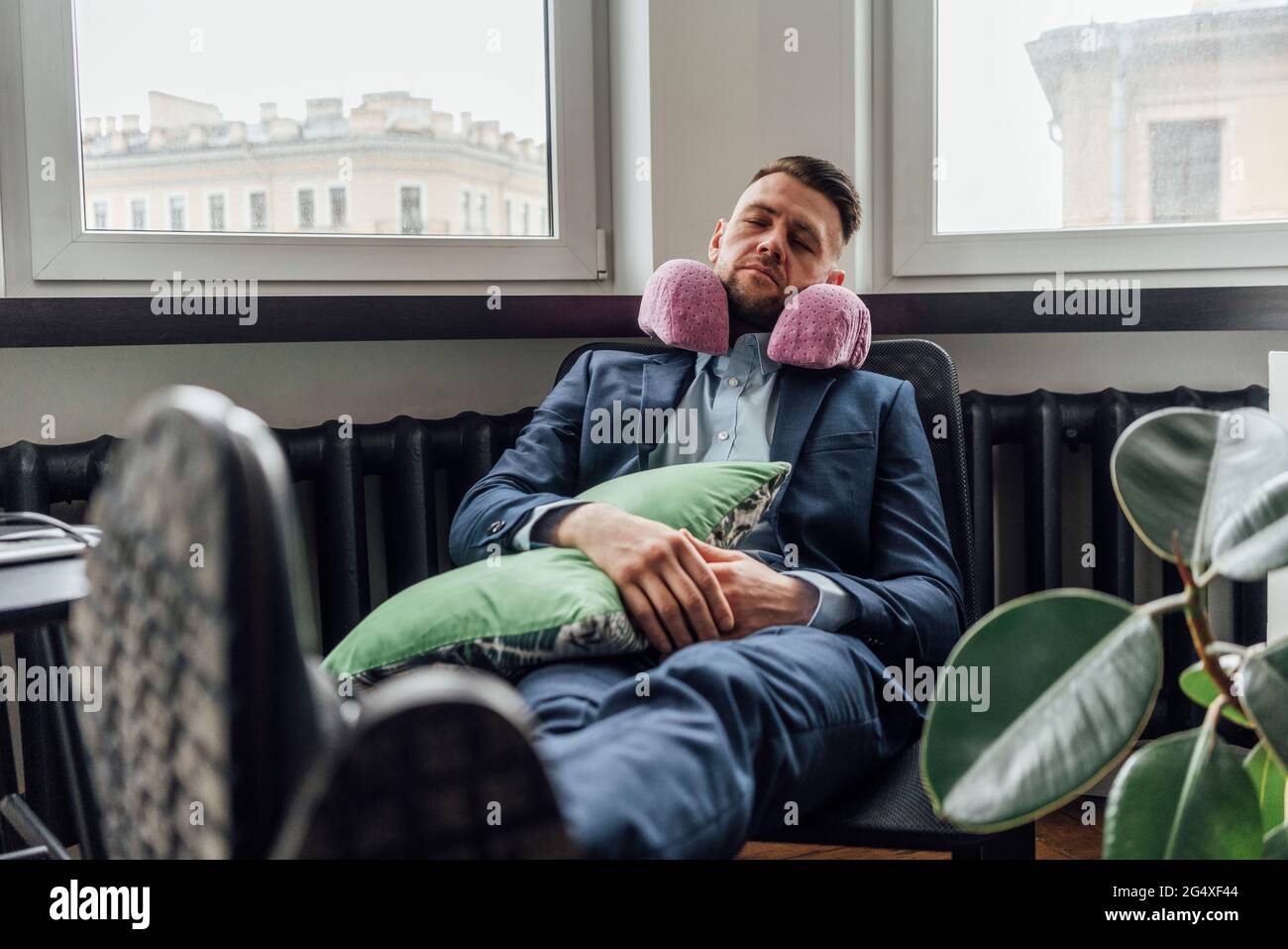 Hombre de negocios con almohada para el cuello relajante en silla en la  oficina Fotografía de stock - Alamy
