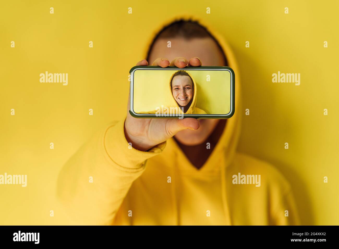 Mujer que muestra la imagen en el smartphone en el estudio Foto de stock