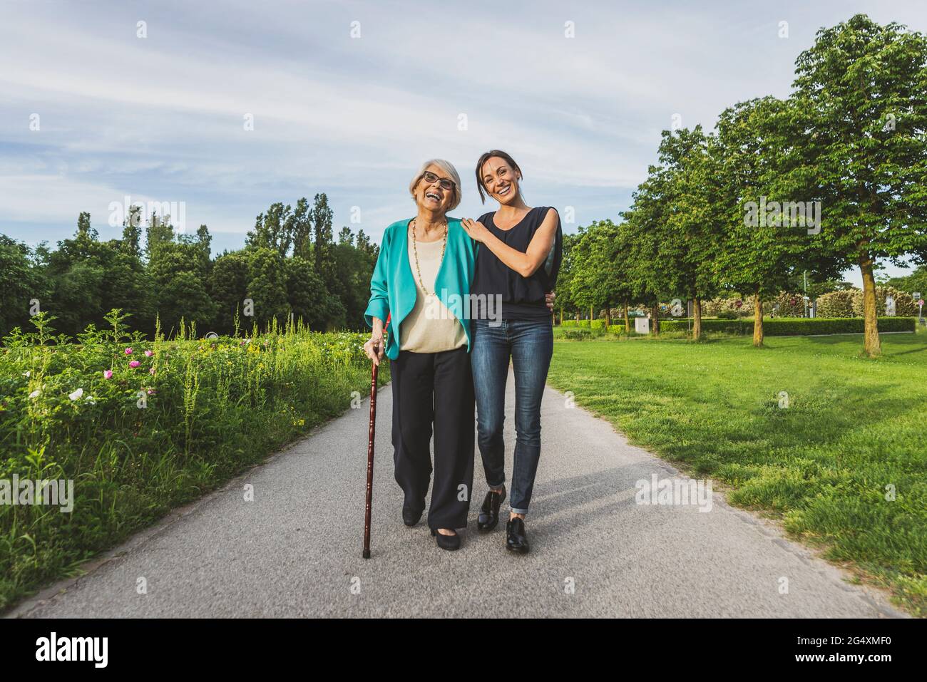 Abuela sonriente y nieta caminando juntos en la carretera en el parque Foto de stock