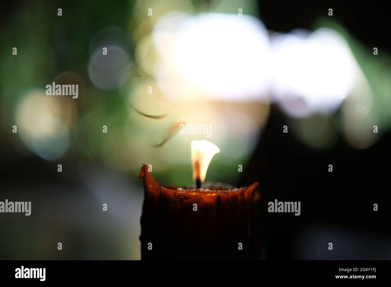 Una vista de cerca de la vela encendida en un templo budista, con llama  brillando a través de cera y remolinos de humo disolviendo a la luz del día  Fotografía de stock -