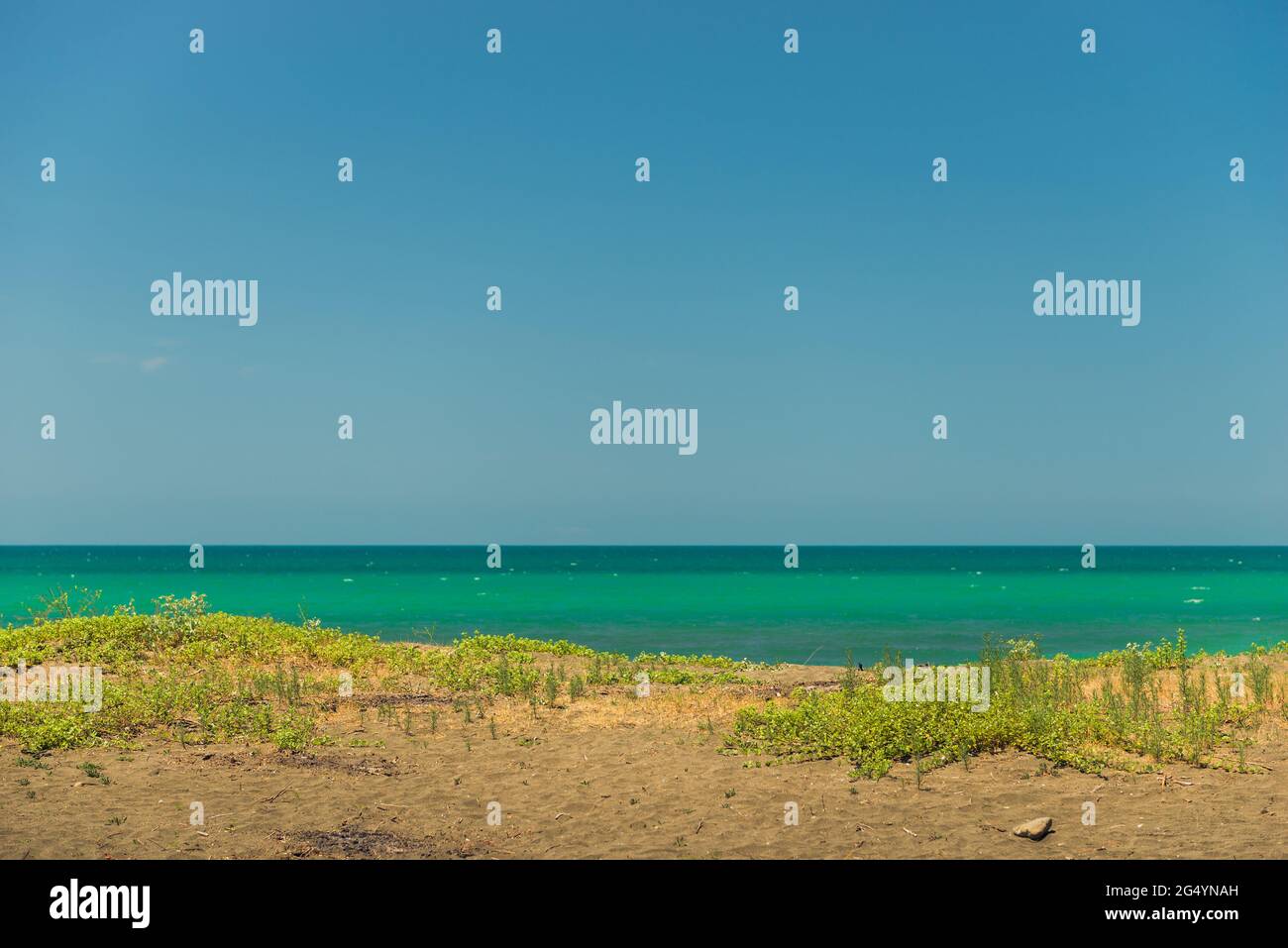 Playa de arena y vista del mar tranquilo en un soleado paisaje de día Foto de stock