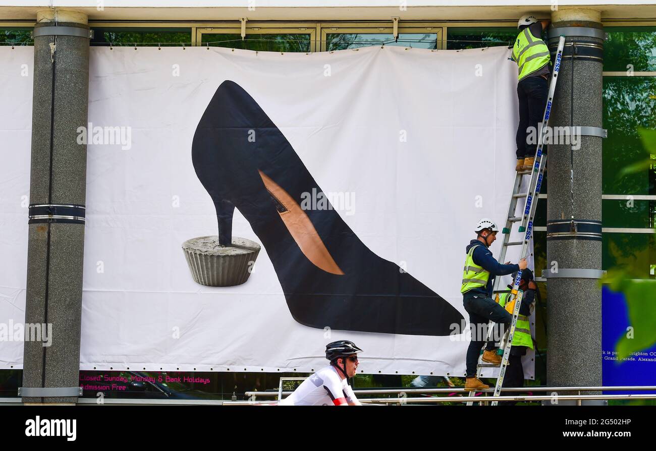 Brighton Reino Unido 24th de junio de 2021 - Banners gigantes que muestran la imagen icónica del stiletto negro de una mujer, de Alexandre da Cunha, anclada en un pastel de hadas concreto, se colocan en el Centro de Artes Contemporáneas de Brighton como parte de la comisión de verano de este año. La comisión de verano es una Serie de obras de arte público en Brighton y año Un artista seleccionado es elegido para crear una nueva obra para el frente de las galerías de Brighton CCA.: Crédito Simon Dack / Alamy Live News Foto de stock