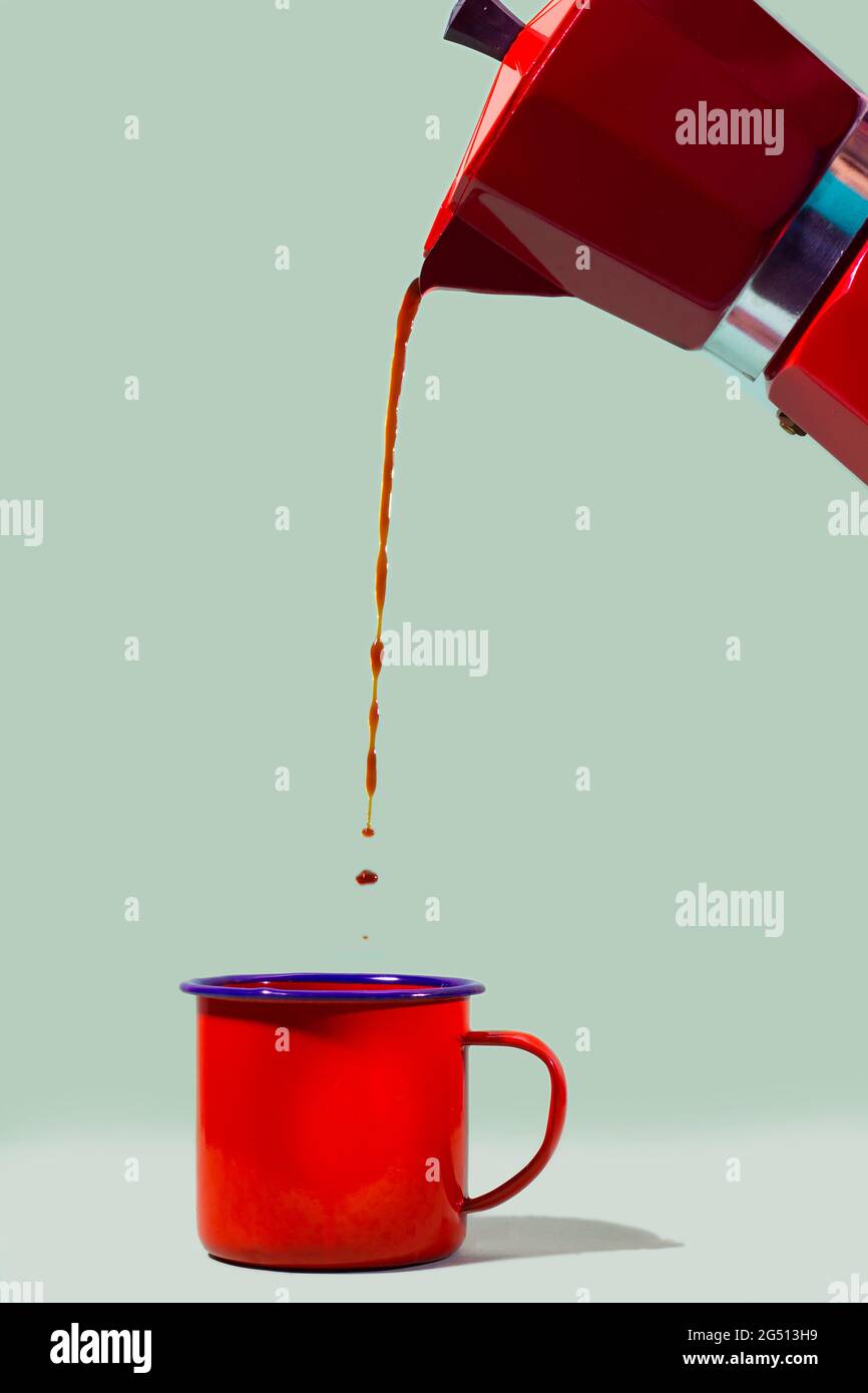 Cafetera italiana que vierte café en la taza roja con fondo verde  Fotografía de stock - Alamy