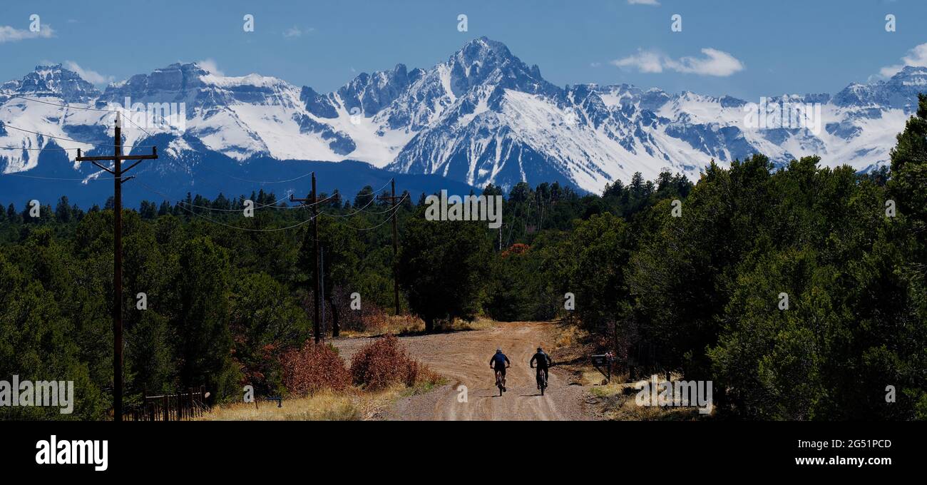 Dos ciclistas montando a lo largo de camino de tierra con montañas en el fondo, Colorado, Estados Unidos Foto de stock
