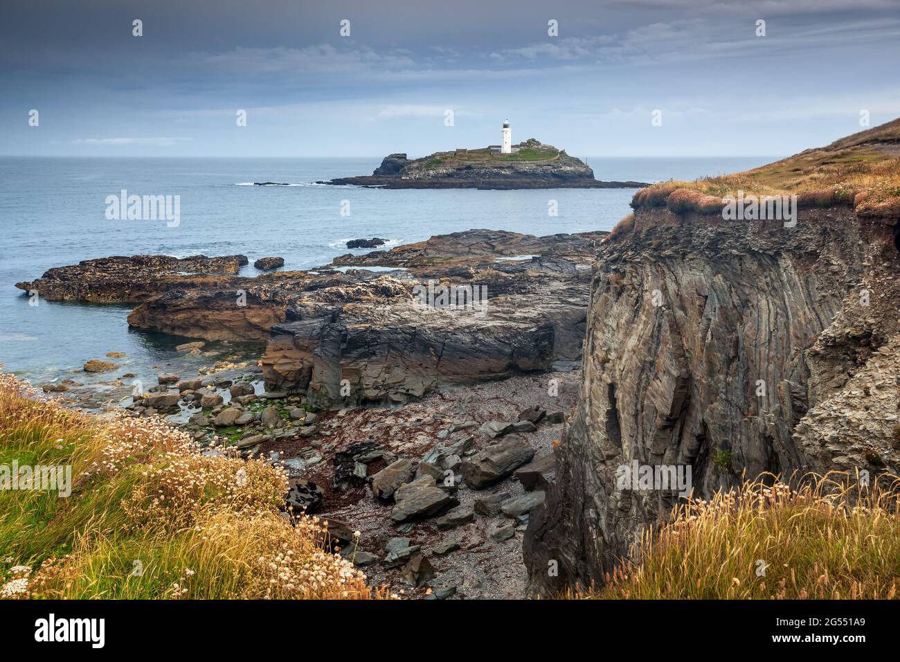 La escarpada costa de cornualles en Godrevy Head vista desde Godrevy Point, con el faro de Godrevy en la distancia. Foto de stock