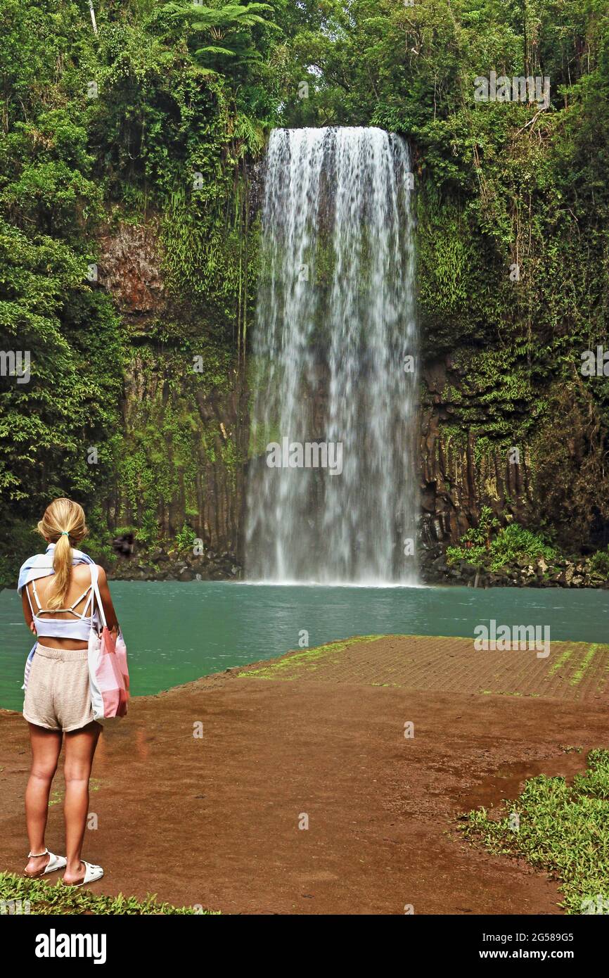 Millaa Millaa Falls y tentadora laguna de natación siendo considerada por una rubia mujer turística durante un día en Atherton Tablelands fuera de Cairns Foto de stock