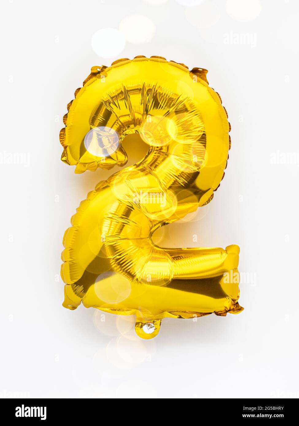 Número 2 decoración de fiesta con globos dorados sobre fondo blanco,  concepto de aniversario de cumpleaños con luces festivas Fotografía de  stock - Alamy