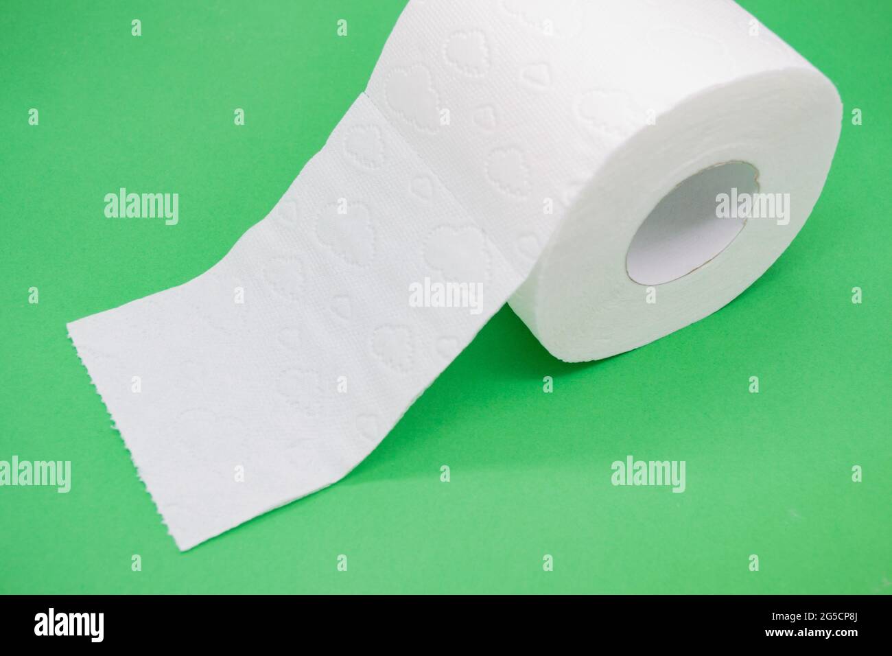 Rollo de papel higiénico blanco con perforación sobre fondo verde. Foto de stock