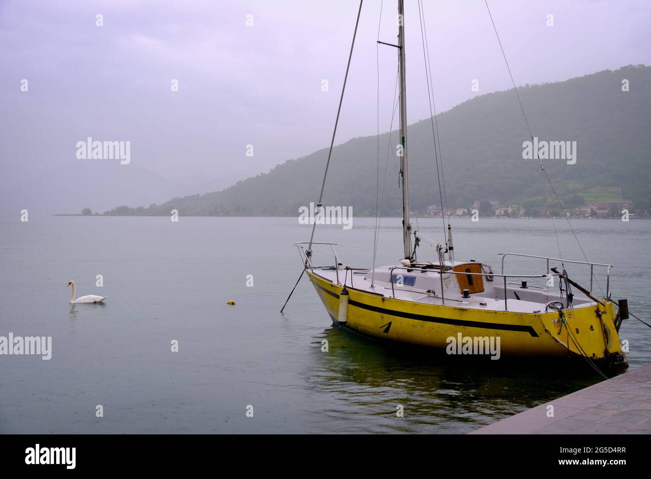 velero amarillo. Día lluvioso en el lago. Lago Iseo, Lombardía, Italia Foto de stock