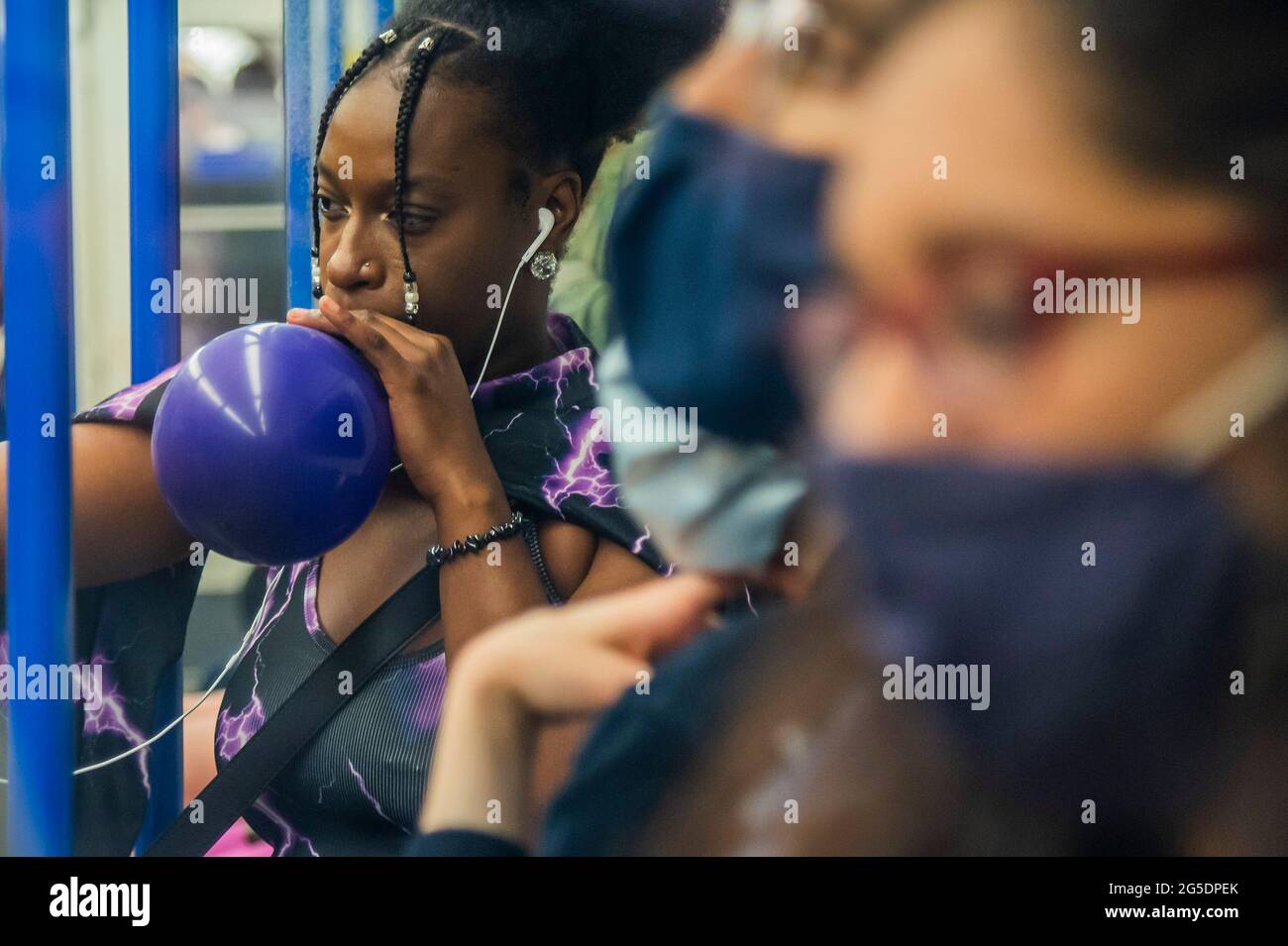 Londres, Reino Unido. 26th de junio de 2021. Una mujer negra desenmascarada se filma y chupa un balón (presumiblemente lleno de óxido nitroso) - el metro está ocupado y muchas personas no usan máscaras ya que nos acercamos al final de las restricciones del coronavirus. Crédito: Guy Bell/Alamy Live News Foto de stock