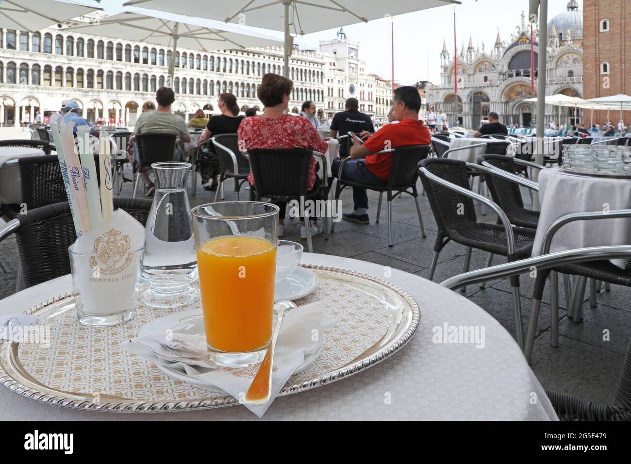 La gente disfruta de la Piazza San Marco desde las mesas de un antiguo bar Foto de stock