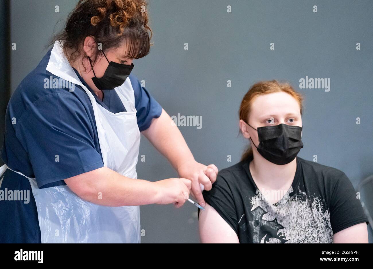 La enfermera Maria Simon (izquierda) vacuna a Sophie Beardsley (derecha) con la vacuna Pfizer Covid-19, en un centro de vacunación contra el coronavirus masivo en el Adwick Leisure Centre, en Doncaster, mientras continúa la campaña de vacunación 'Grab a jab' del NHS en Inglaterra. Fecha de la foto: Domingo 27 de junio de 2021. Foto de stock