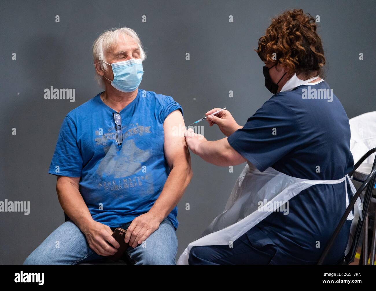 La enfermera Maria Simon (derecha) vacuna Geoff Corner (izquierda) con la vacuna Pfizer Covid-19, en un centro de vacunación contra el coronavirus masivo en el Adwick Leisure Centre, en Doncaster, mientras continúa la campaña de vacunación del NHS 'Grab a jab' en Inglaterra. Fecha de la foto: Domingo 27 de junio de 2021. Foto de stock