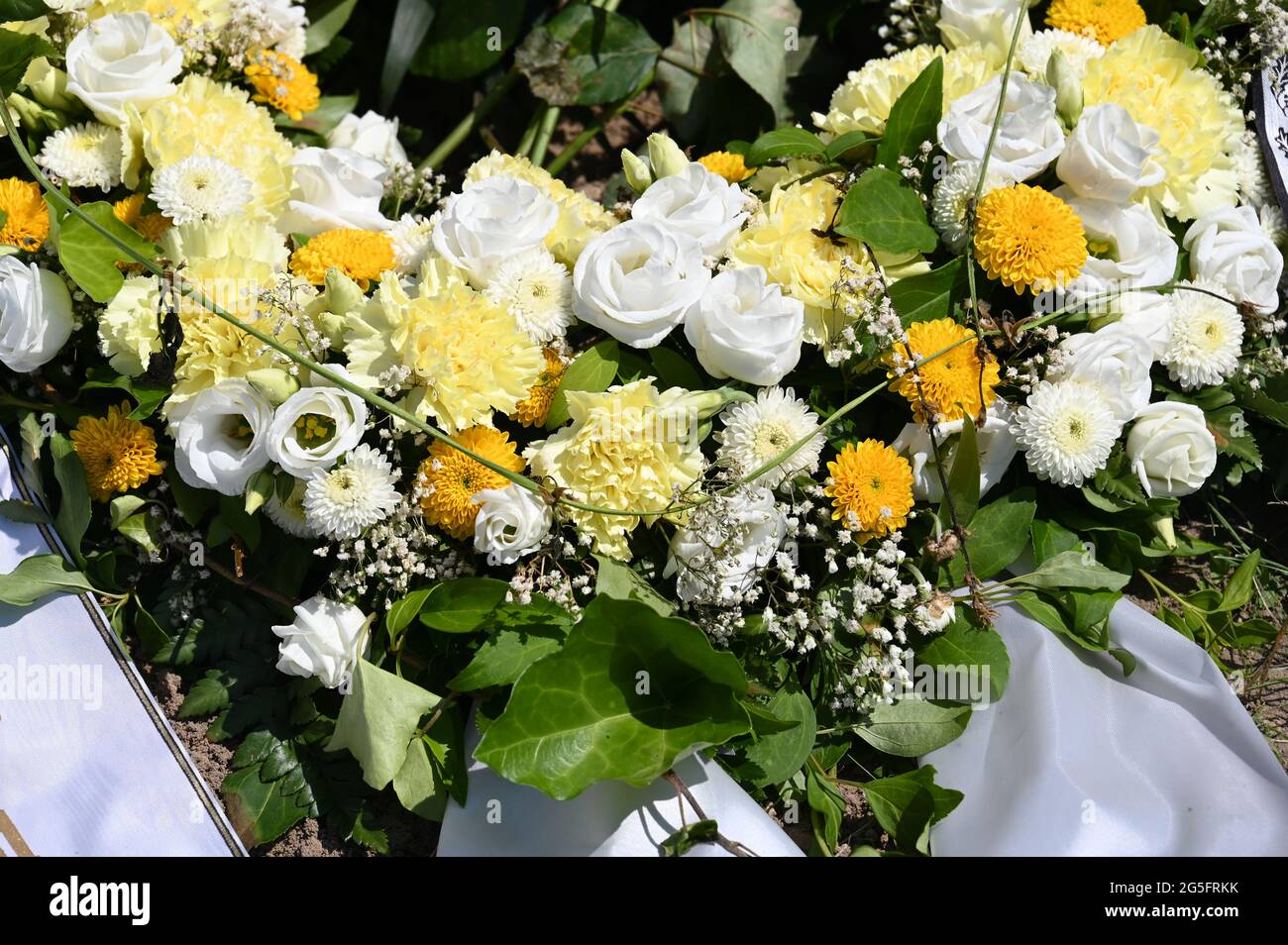 Corona de flores blancas y amarillas en una tumba Foto de stock
