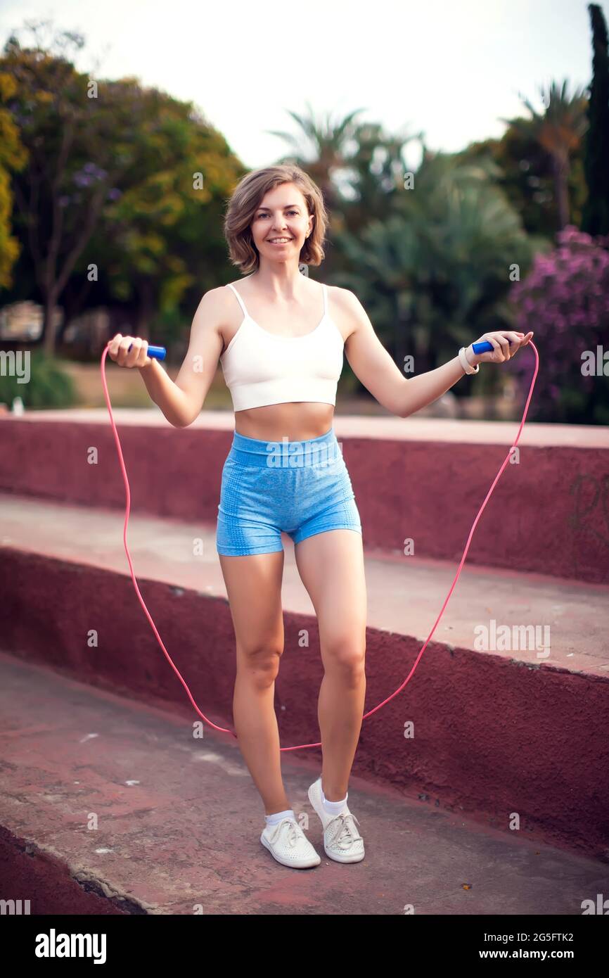 Mujer con cuerda que salta. Haga ejercicio en el parque. Concepto de deporte y salud Foto de stock