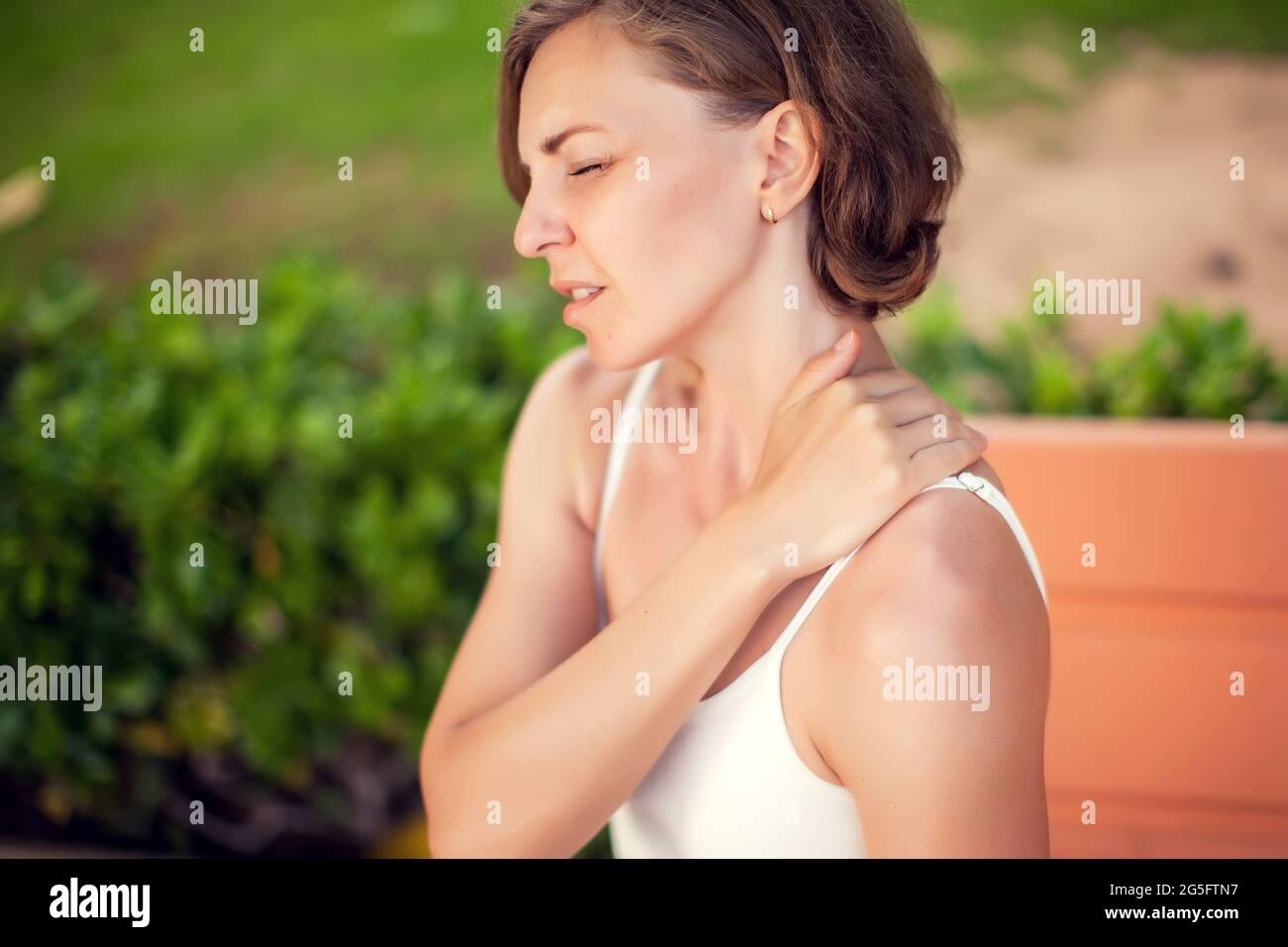 Dolor de cuello. Mujer que siente dolor en el cuello o en el hombro al aire libre. Concepto de salud y estilo de vida Foto de stock