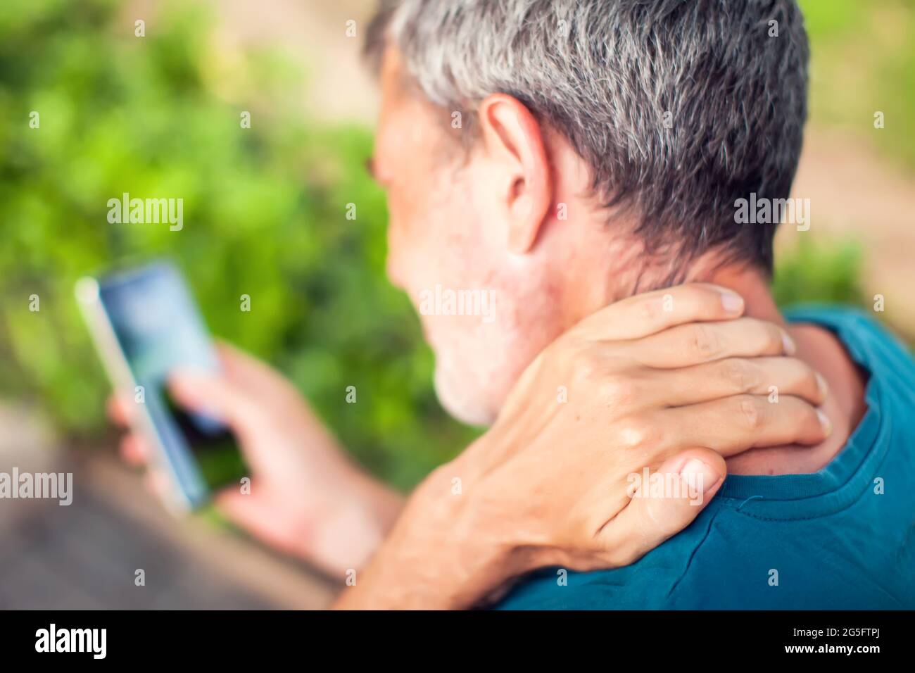 Dolor de cuello con el smartphone al aire libre. Concepto de salud, estilo de vida y tecnología Foto de stock